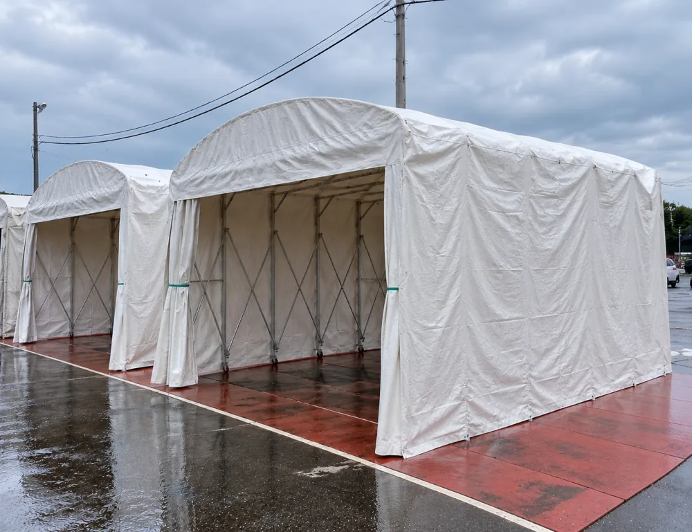 屋外で雨よけとして設置されたアーチ型のキャスター式伸縮テント2棟並び