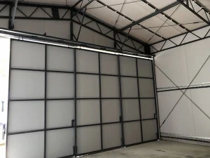 テント倉庫の内部から見た格子状の骨組みを持つ正面のシートドア