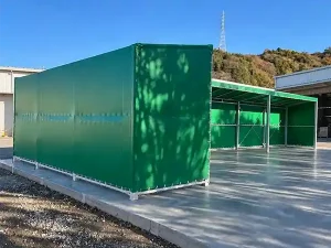 グリーンの側面シートで囲った荷捌きテントと前面の様子